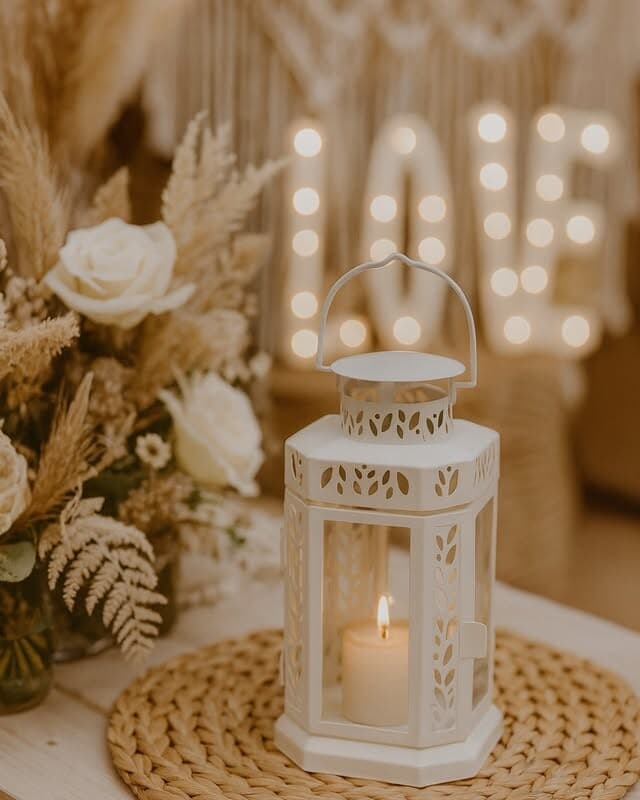 A charming white lantern with bohemian detailing. Works beautifully lined along aisle paths, clustered on reception tables, or placed on display plinths. Insert a candle or LED light for warm, inviting glow. The white finish complements any setting.
